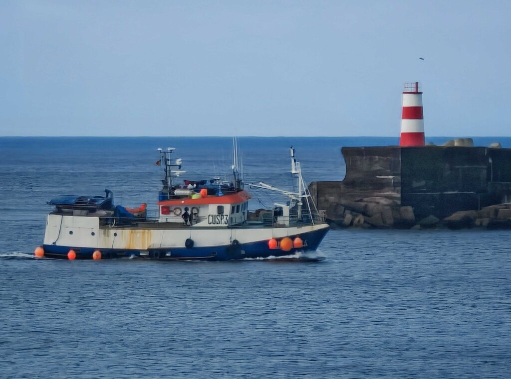 A fishing boat sailing near a lighthouse with red and white stripes, set against a calm sea.
